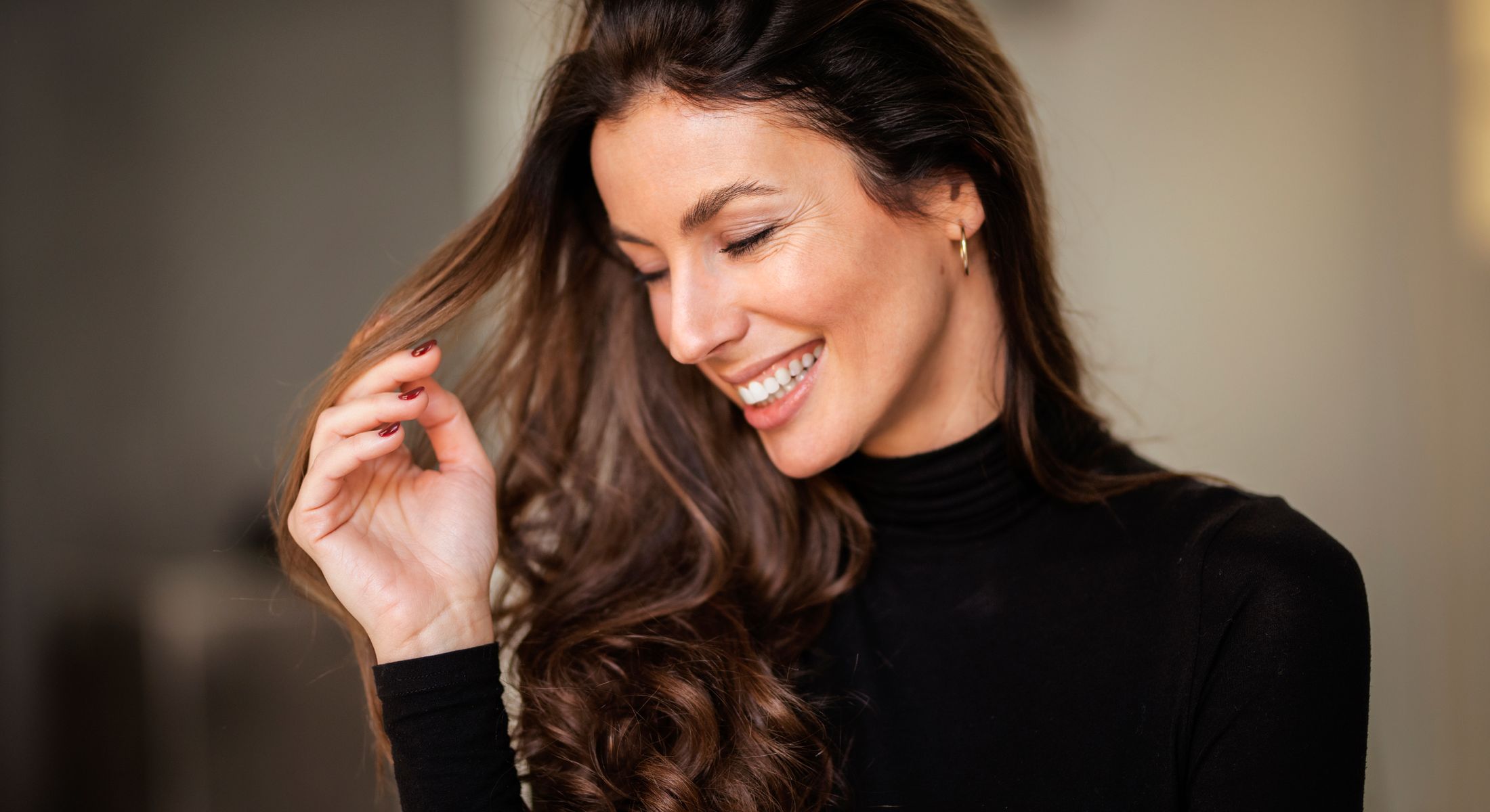 Smiling woman with long, wavy hair indoors.