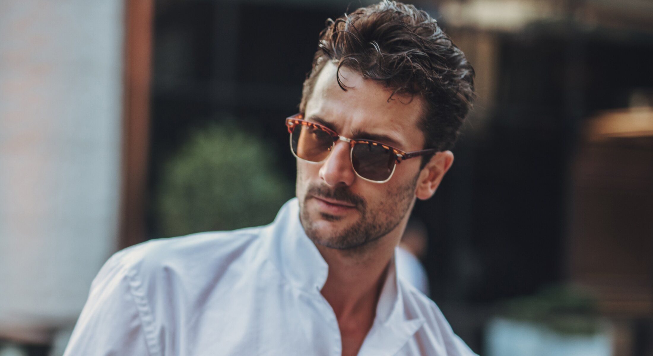 Man in sunglasses wearing a white shirt.