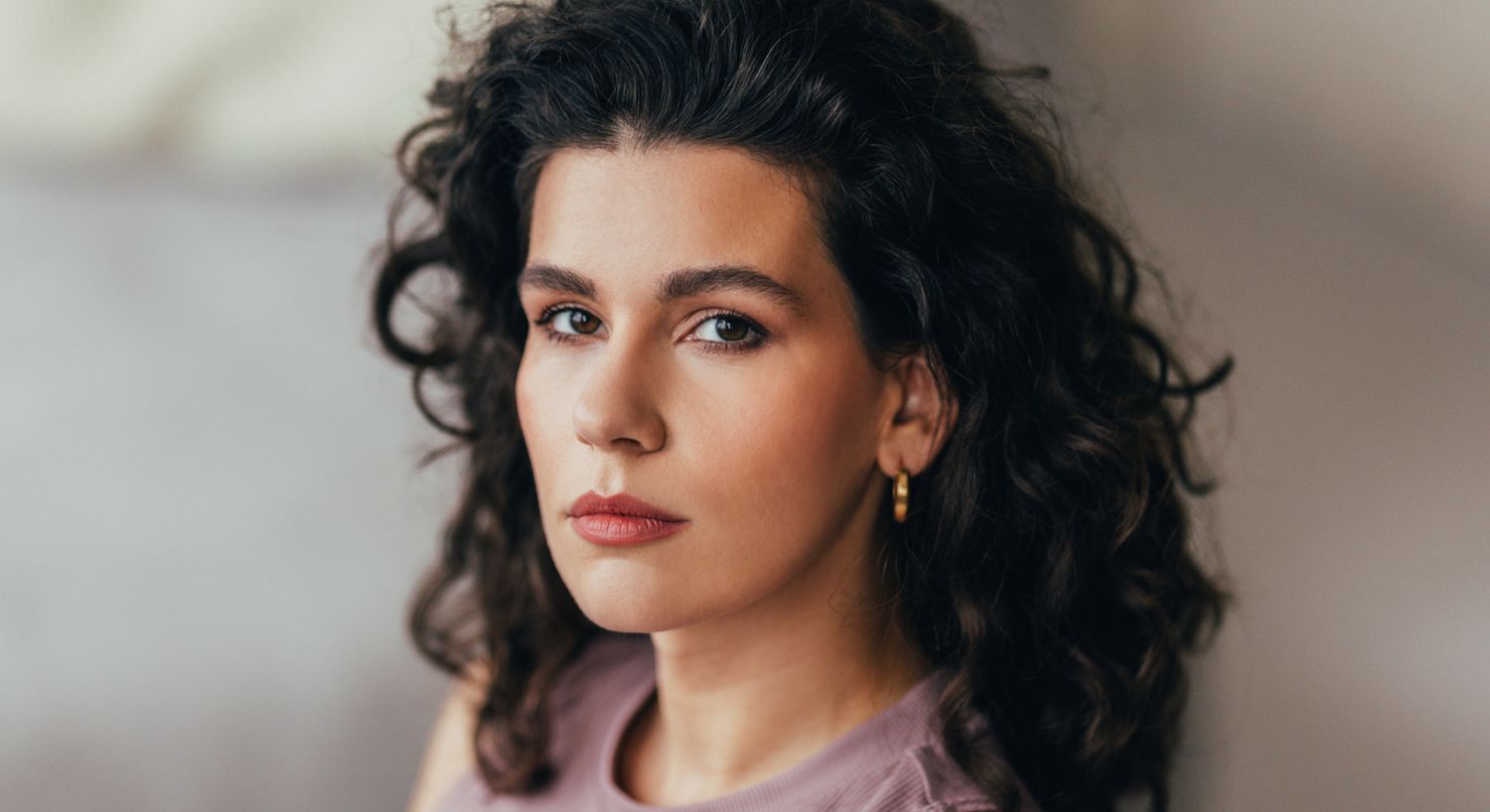 Woman with curly hair and natural makeup.