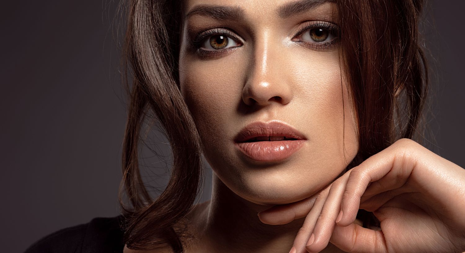 Woman posing elegantly with stylish makeup.