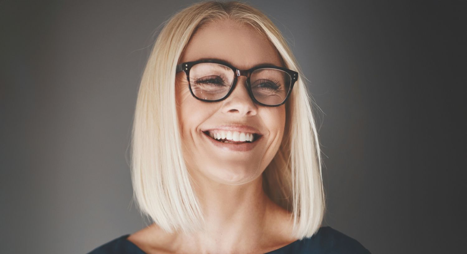 Smiling woman with glasses and blonde hair.