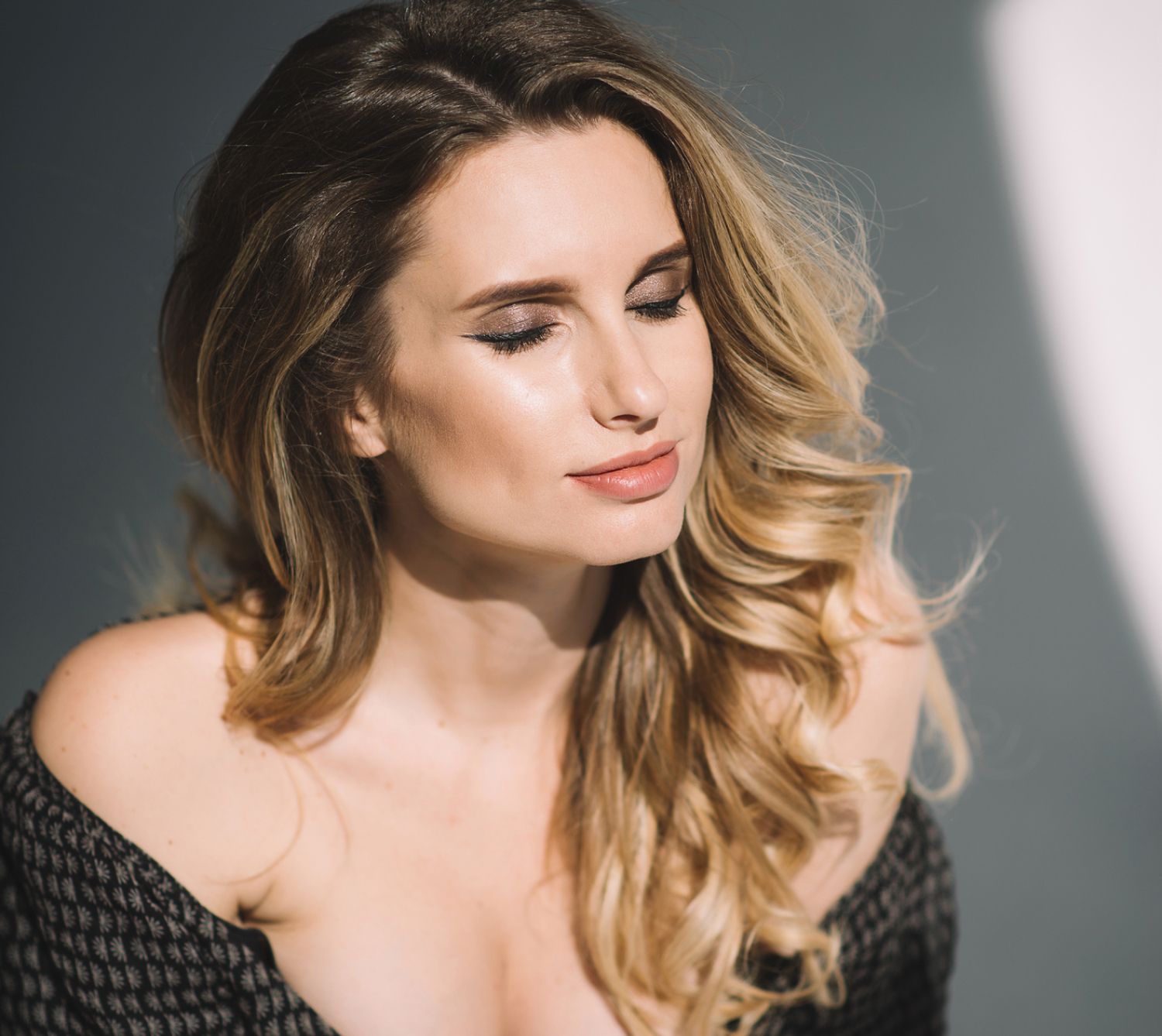 Woman with soft curls, eyes closed, serene expression.